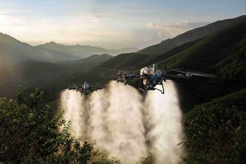 Irrigation drone spraying water over uneven hilly terrain and terraced fields for precision agriculture